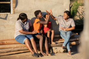 Esther Mtsweni, far right, and another Mentor Mother engage with children during a household visit