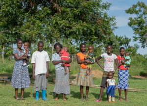 m2m clients in Uganda posing with their children, flashing smiles to the camera and looking healthy. 