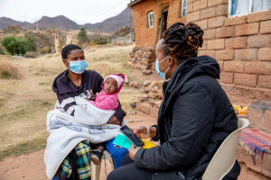 m2m Mentor Mother with a client and her daughter outside their home in Lesotho.