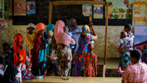Mothers and their babies in their arms queuing to speak to a health worker and have their baby weighed. These services are at risk since the recent global aid cuts.
